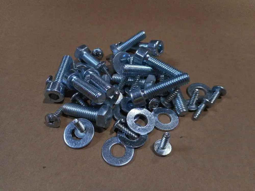 Metallene Schrauben und Unterlegscheiben liegen lose auf braunem Hintergrund. Produkte von Remeha, geeignet für verschiedene Befestigungsanwendungen.